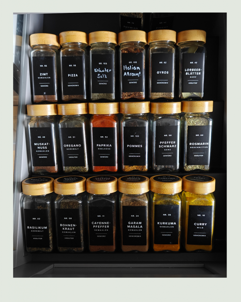 Ordentlich sortierte Gewürzschublade mit einheitlichen Gewürzgläsern