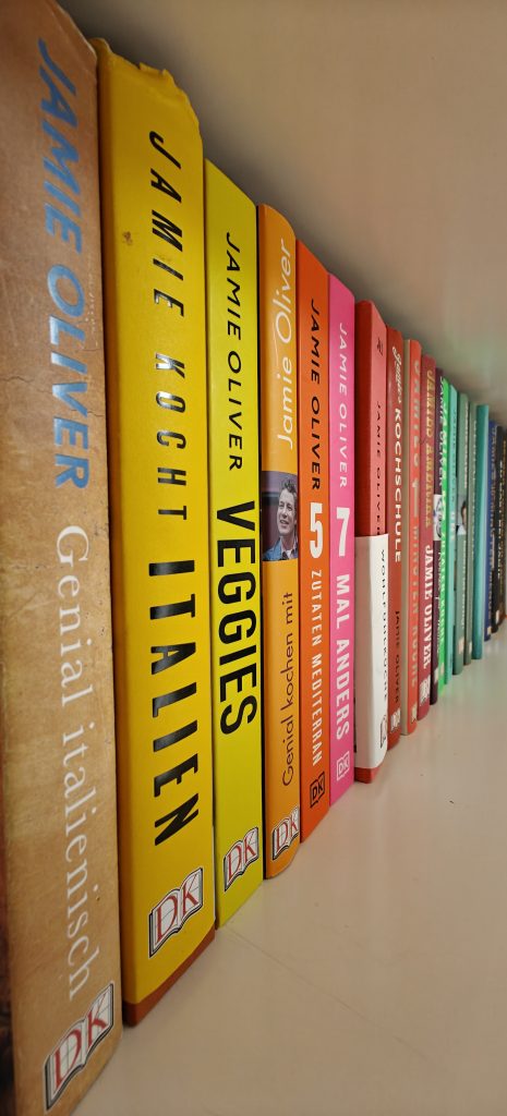 Detailaufnahme eines Bücherregals, indem die Bücher nach Regenbogenfarben sortiert sind